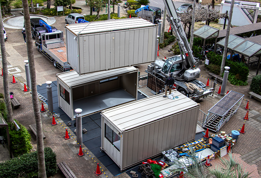 組立ハウスを設置する作業員と完成した仮設事務所