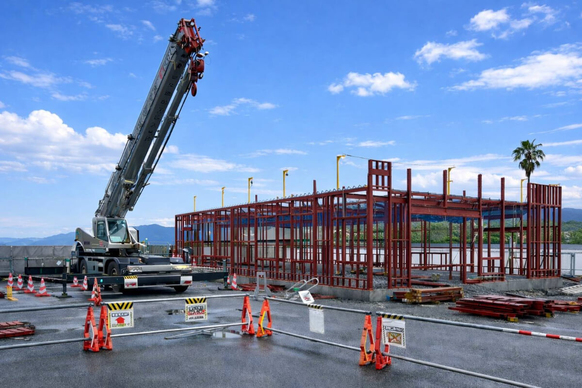 クレーンで軽量鉄骨を組み上げる建設現場
